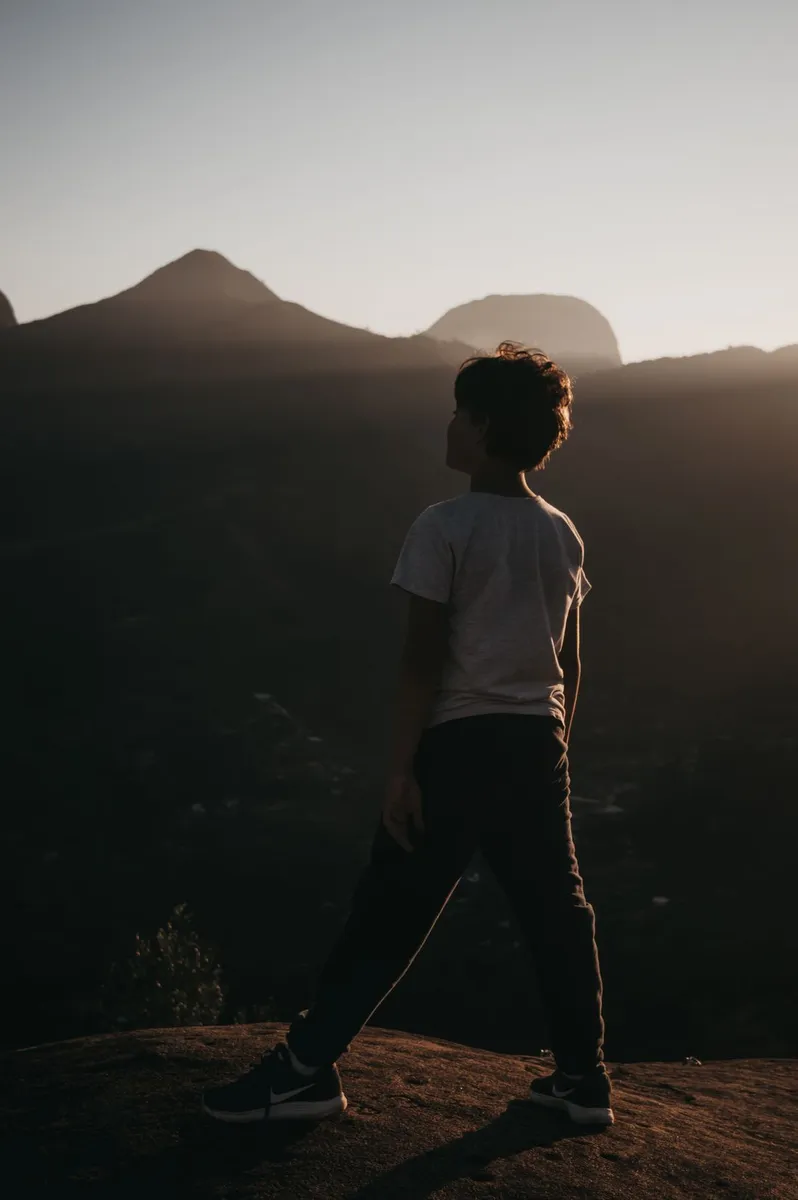 Adolescente visto de espaldas contemplando un paisaje montañoso, imagen referencial sobre la construcción de la identidad